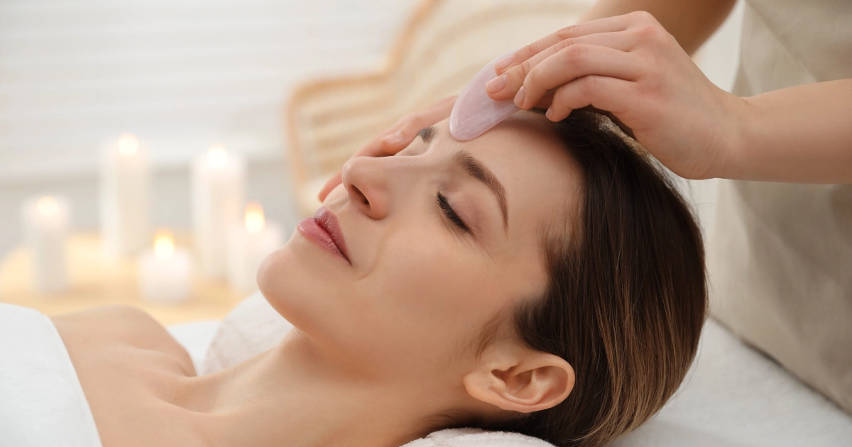 Woman receiving a facial massage with a crystal gua sha tool during a Gua Sha Facial in Meridian, ID.