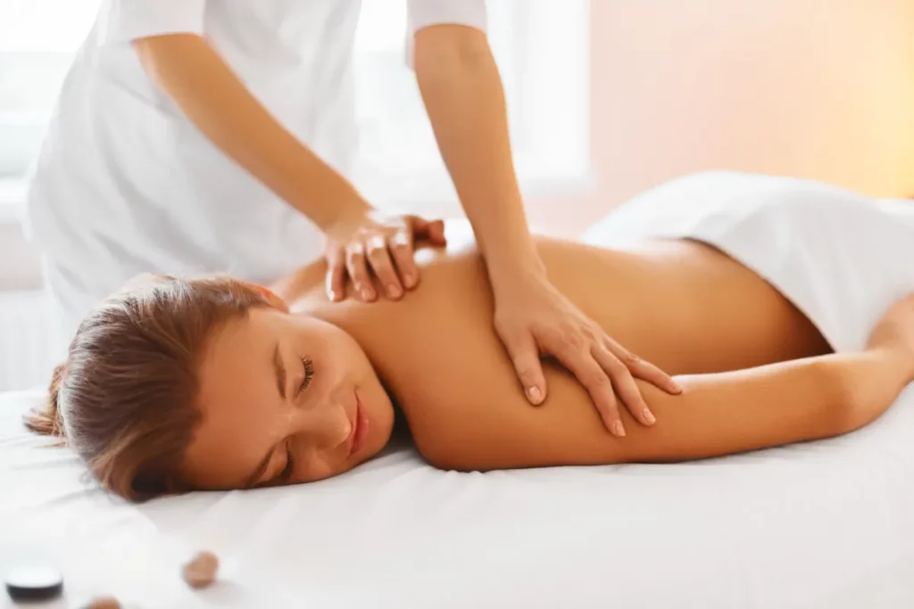 a woman lying down on a bed with hands on the back