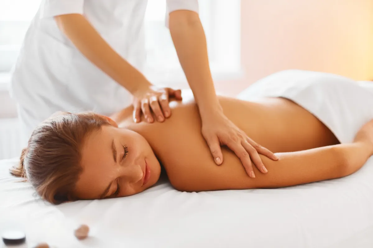 a woman lying down on a bed with hands on the back